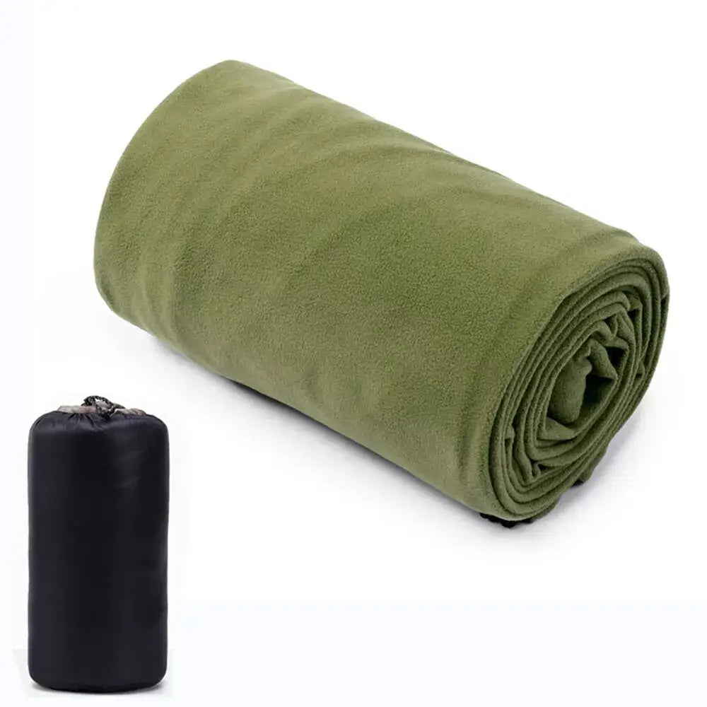 Rolled-up green fleece blanket next to a black storage bag.