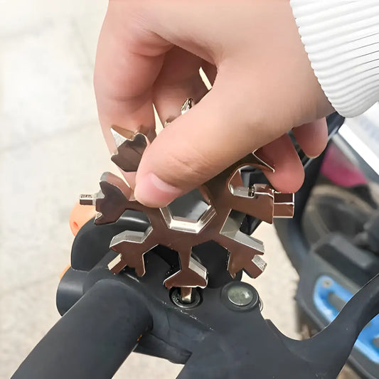 Metallic snowflake-shaped multi-tool being held between fingers.