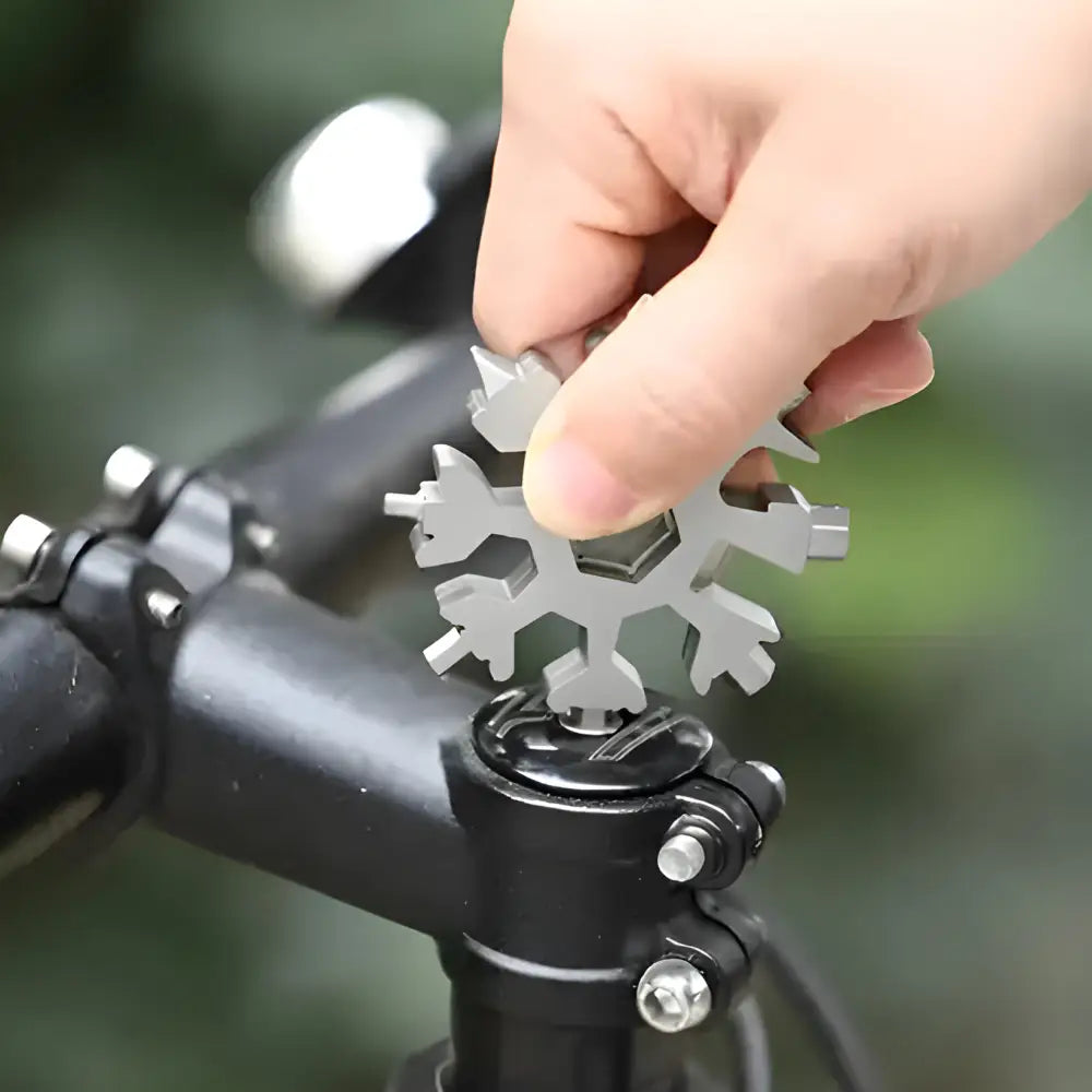 Snowflake-shaped multi-tool being held over a bicycle handlebar.