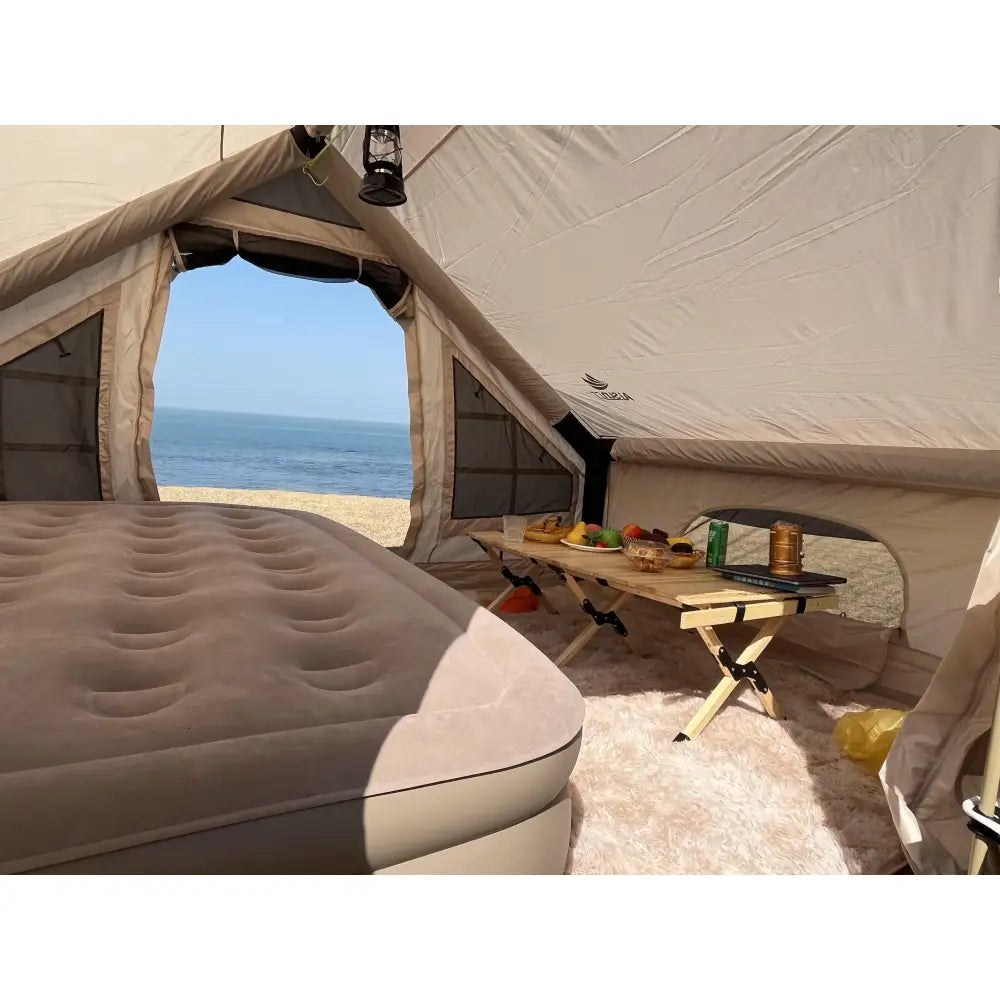 Tent with an air mattress and folding table overlooking the ocean.