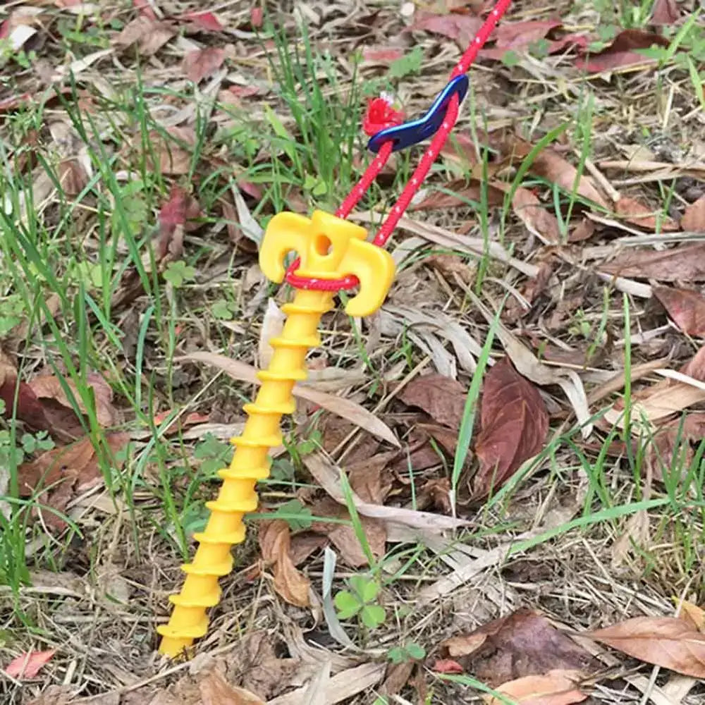 Yellow plastic screw-in tent stake or ground anchor with a red cord attached.