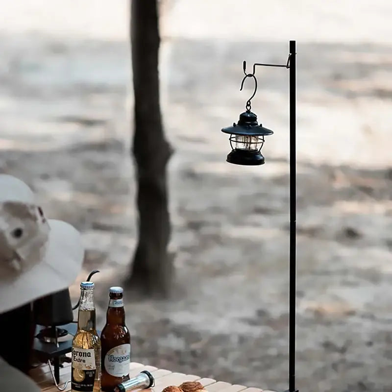 Lantern hanging from a metal pole near a beach setting.