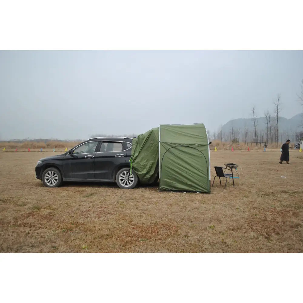 SUV with an attached green tent in a field.