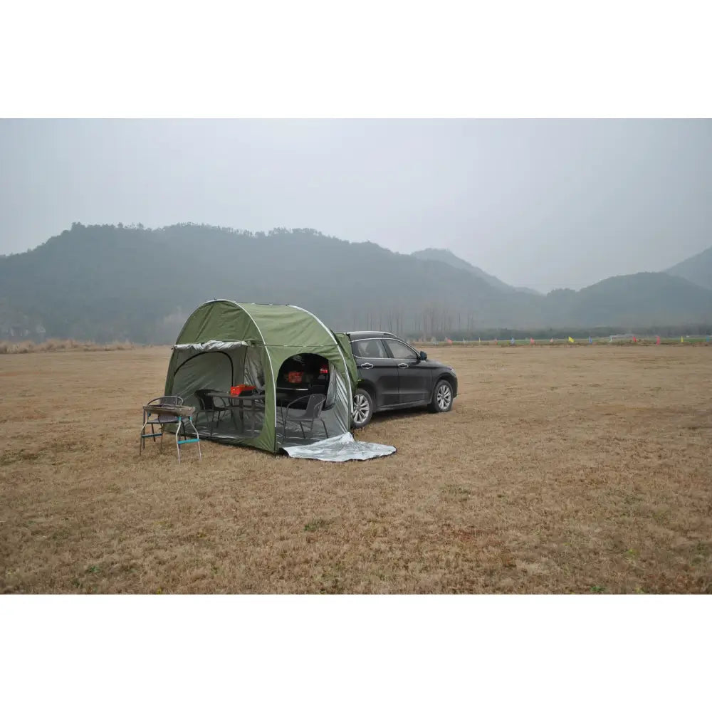 Green camping tent attached to the side of a black SUV.