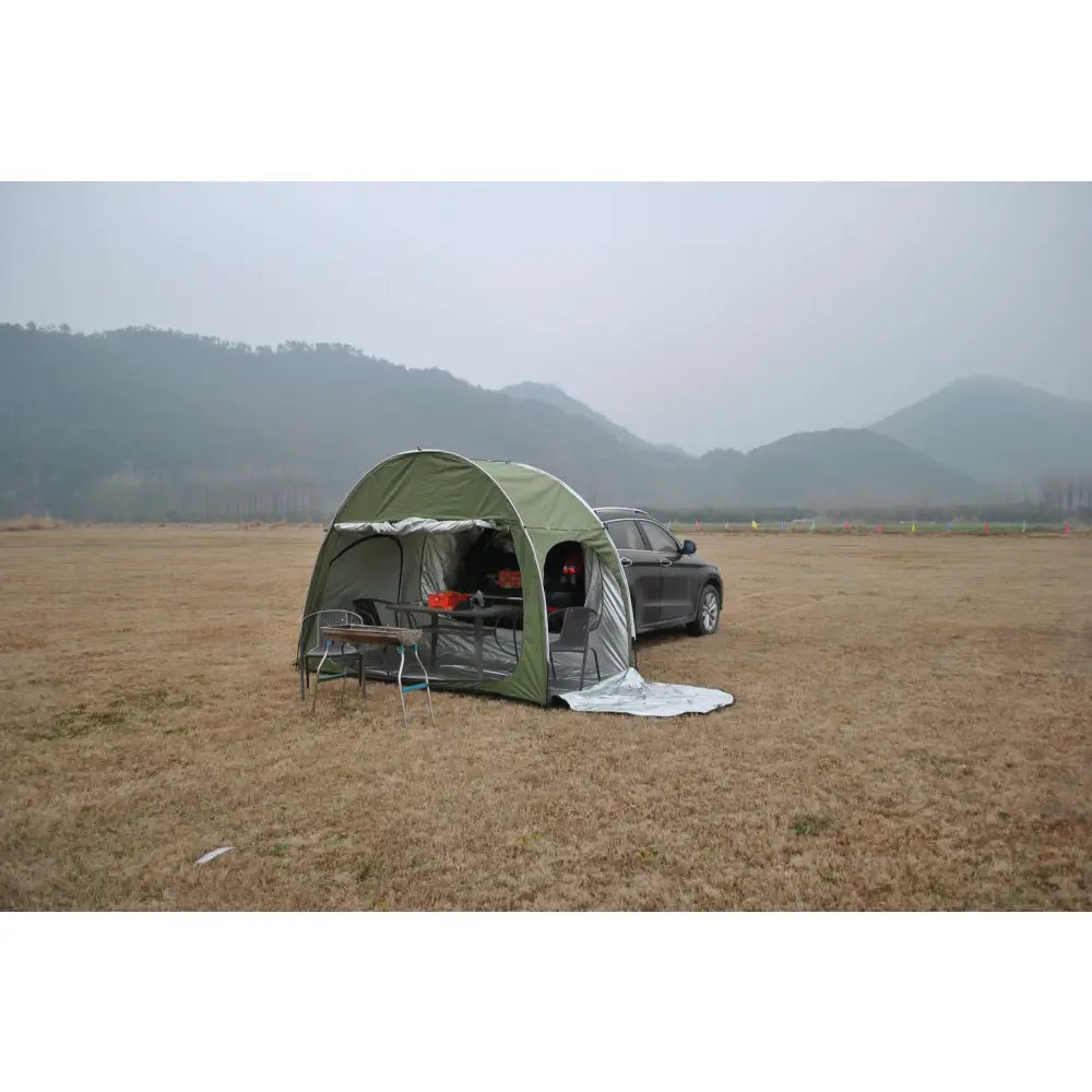 Green camping tent attached to the side of a car.