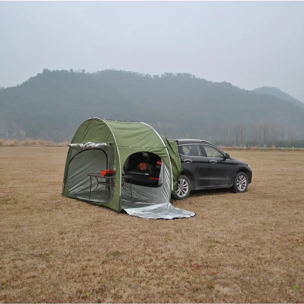 Green camping tent attached to the side of a dark-colored SUV.