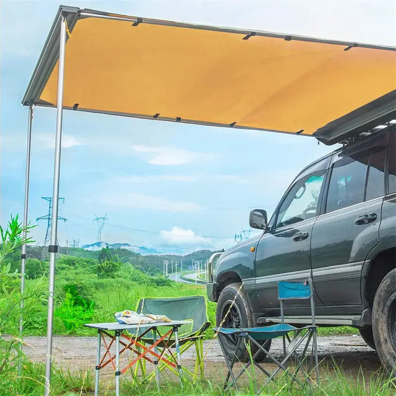 SUV with an attached awning parked in a rural setting.