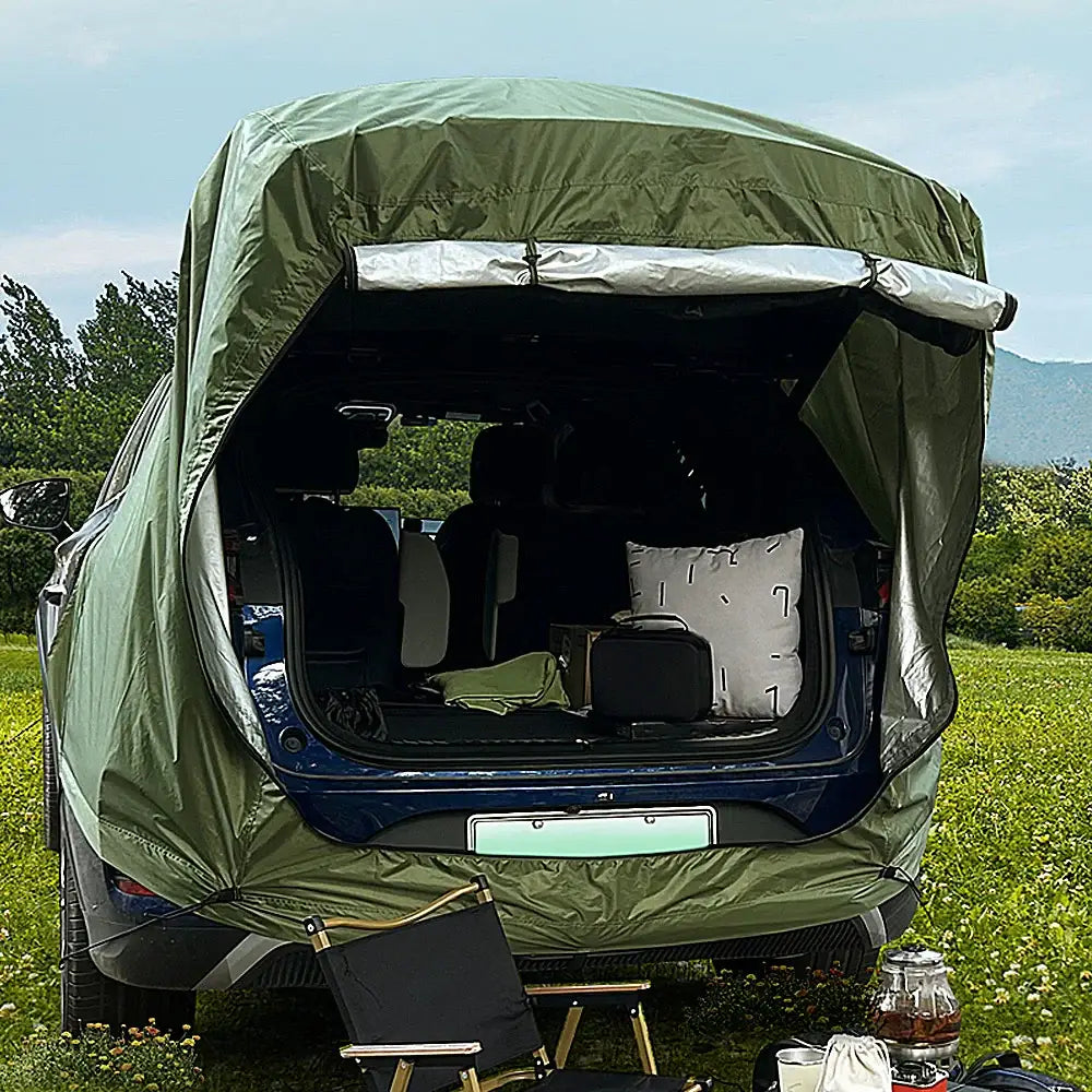 Camping vehicle with an open rear hatch covered by a green canopy.