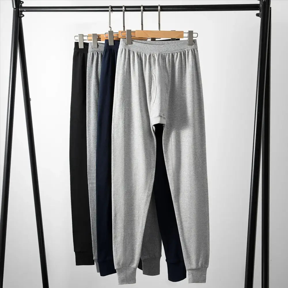 Sweatpants in three colors hanging on a clothing rack.