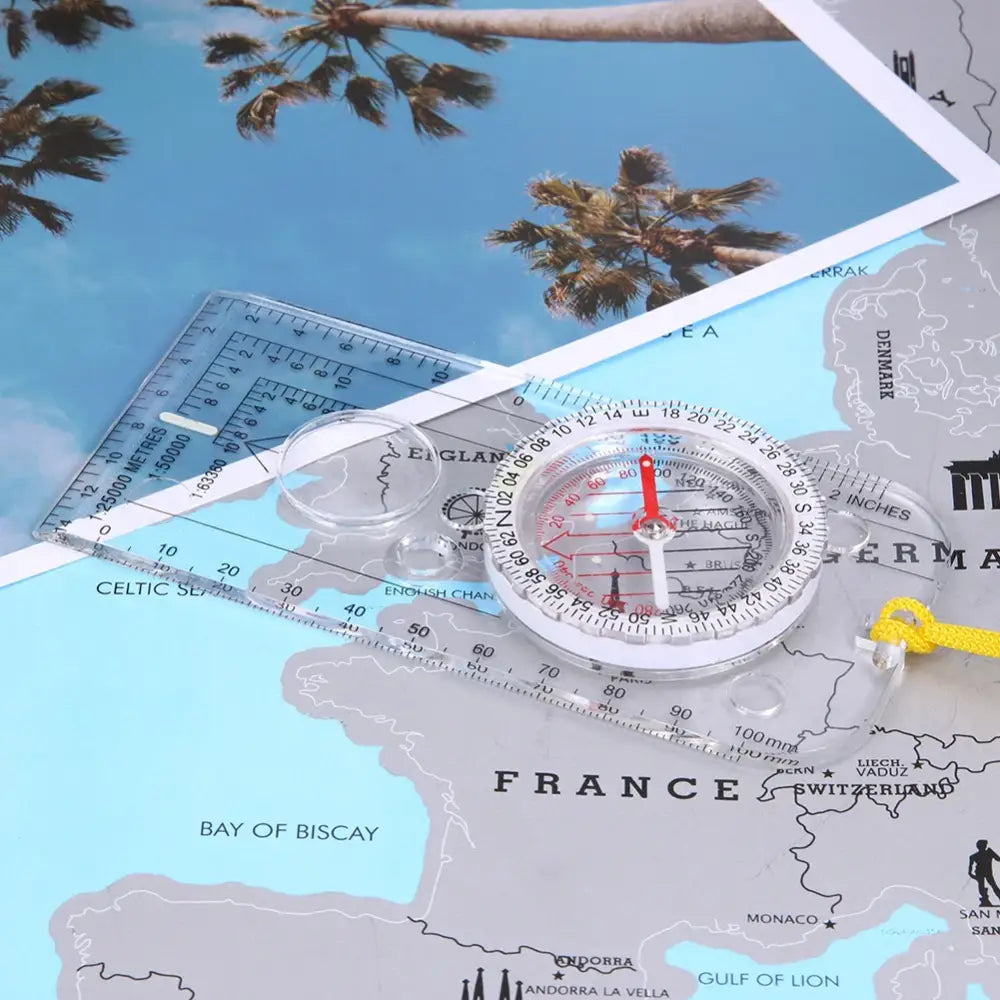 Compass sitting on a map of Europe with palm trees visible in the background.