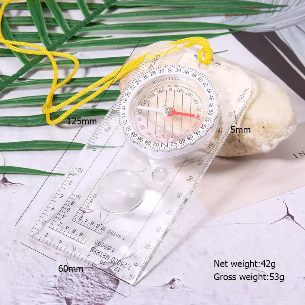 Transparent plastic compass with measurement markings and a yellow lanyard.