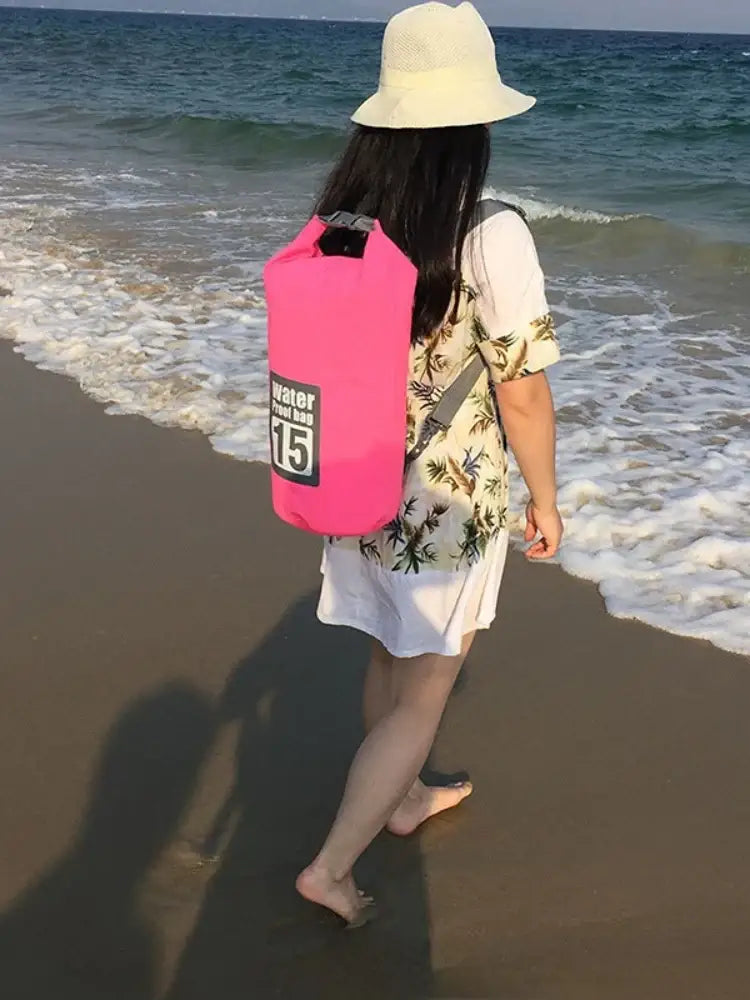 Pink waterproof dry bag carried by a beachgoer.