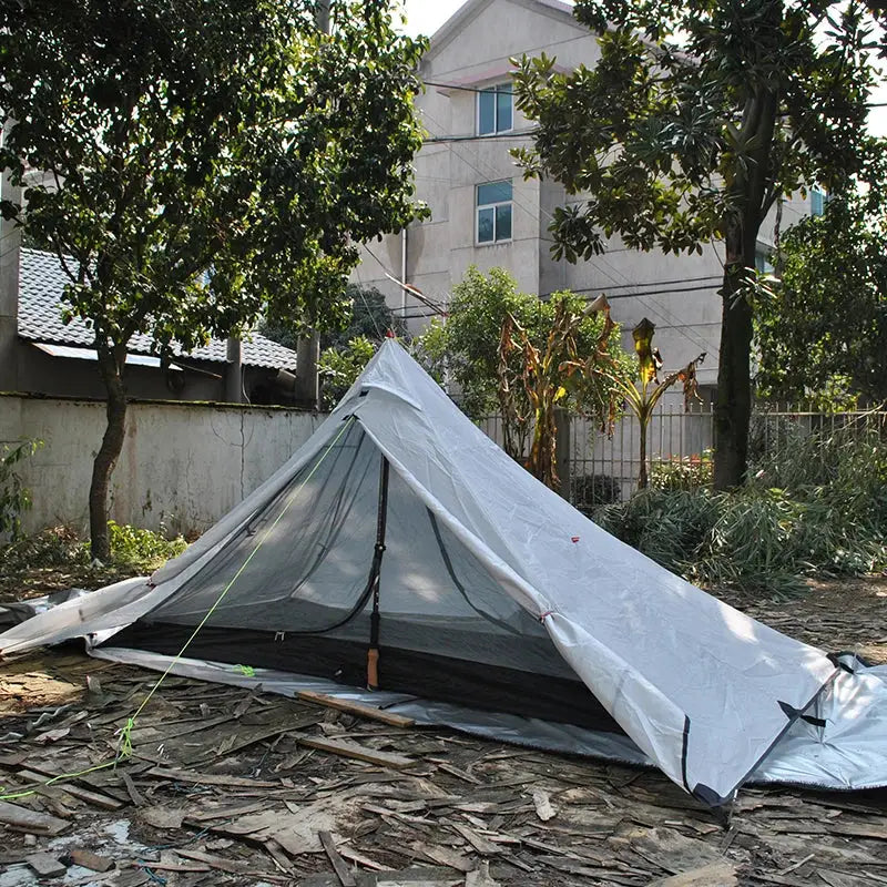 Lightweight camping tent pitched on leafy ground.