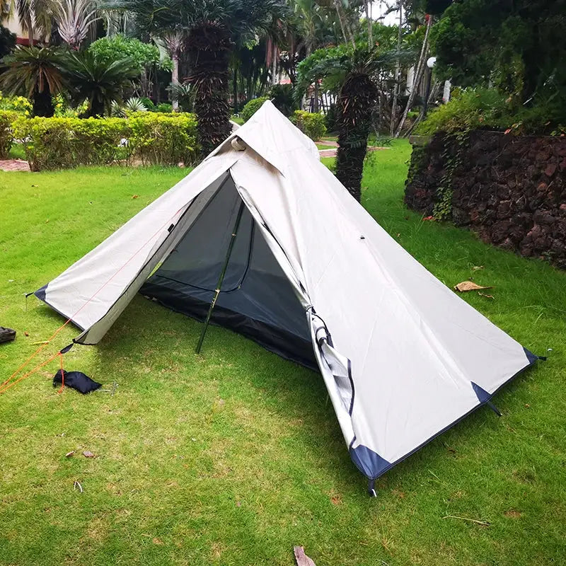 White triangular tent pitched on grass.