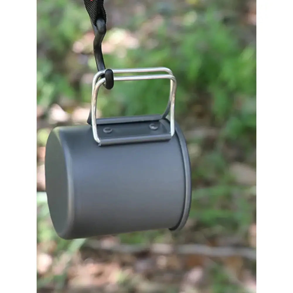 Cylindrical metal mug or cup with a folding handle suspended by a cord.