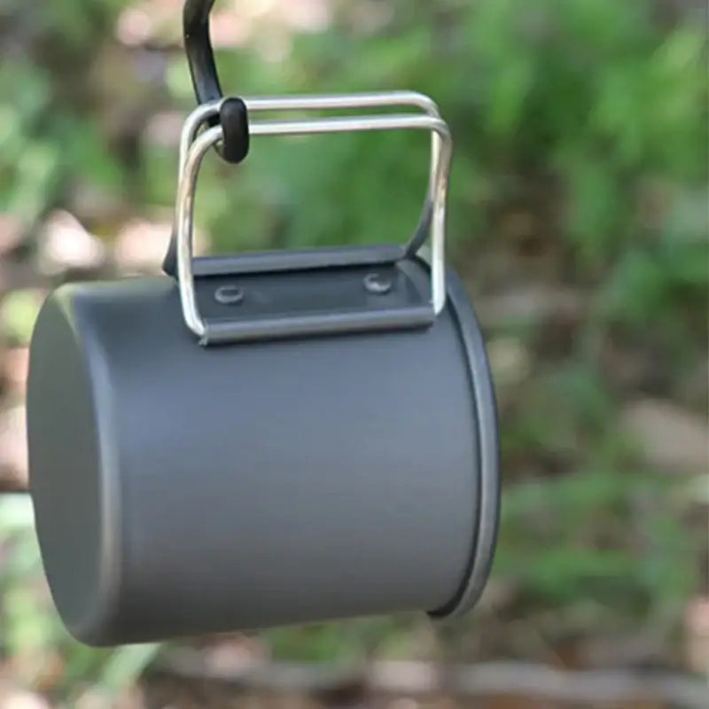 Cylindrical metal mug or cup with a folding handle attached.