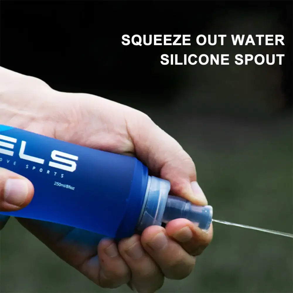 Blue sports water bottle with a silicone spout being squeezed to dispense water.